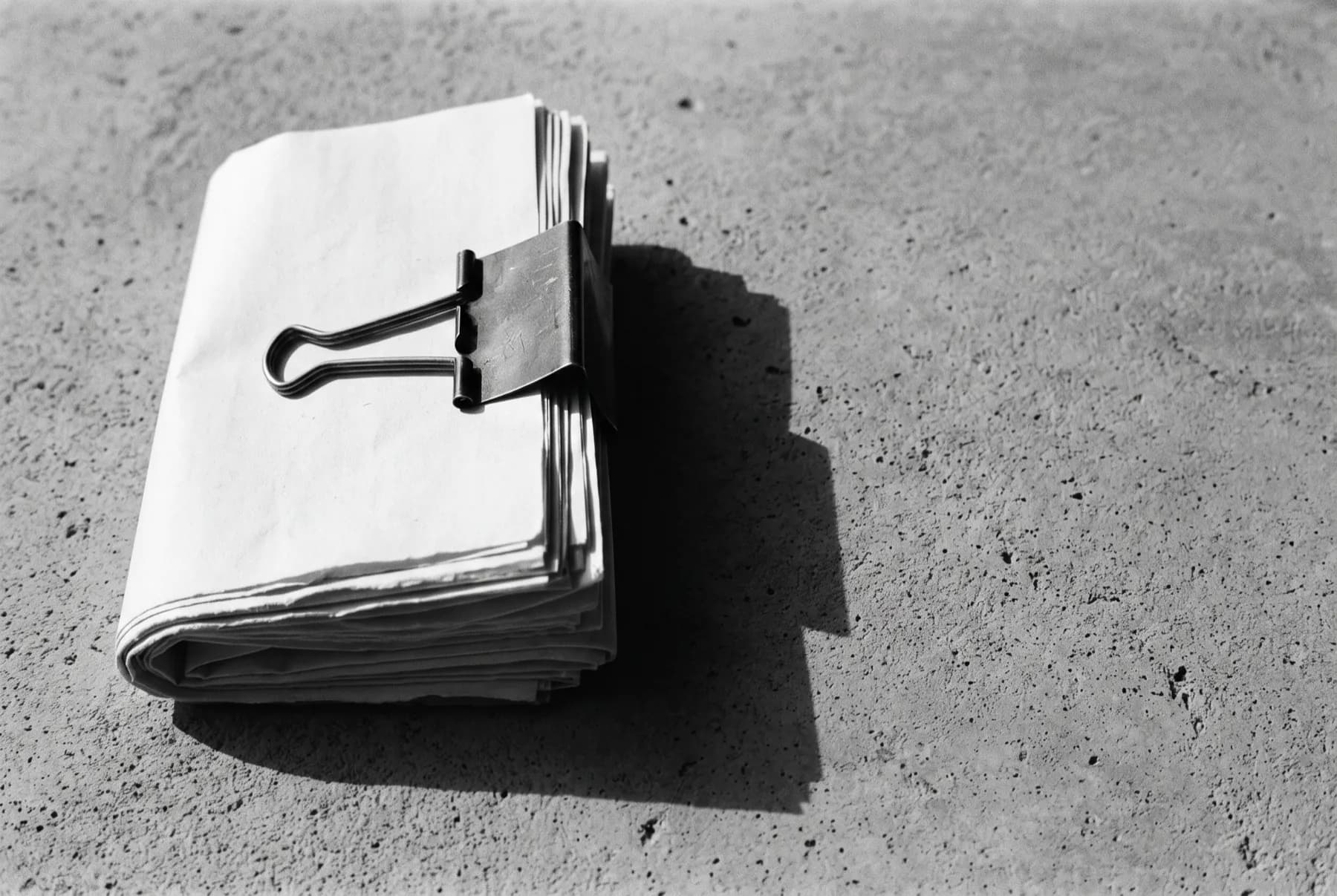 Dossier de documents agrafé, posé sur du béton brut